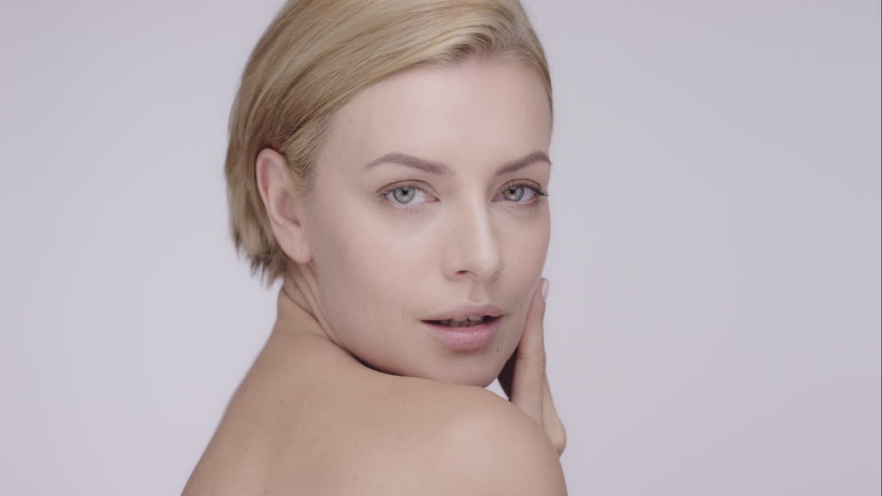 Beautiful healthy woman touching smooth skin on face in slow motion for beauty skincare concept on a grey background Red Epic Dragon