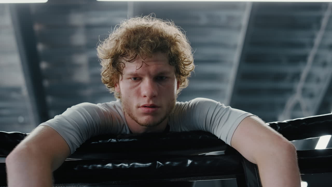 피곤 한  ⁇ 박서 가 체육관 에서 로프 에 의지 하고 있다. 전투기 가 피트니스 센터 에서 전투 를 패배 시키고 있다