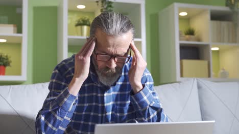 dolor de cabeza. el hombre que mira mucho la computadora portátil y trabaja duro tiene dolor de cabeza.