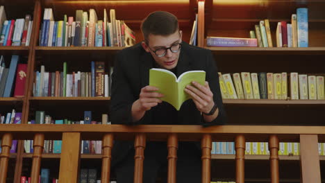 un joven leyendo un libro en una biblioteca