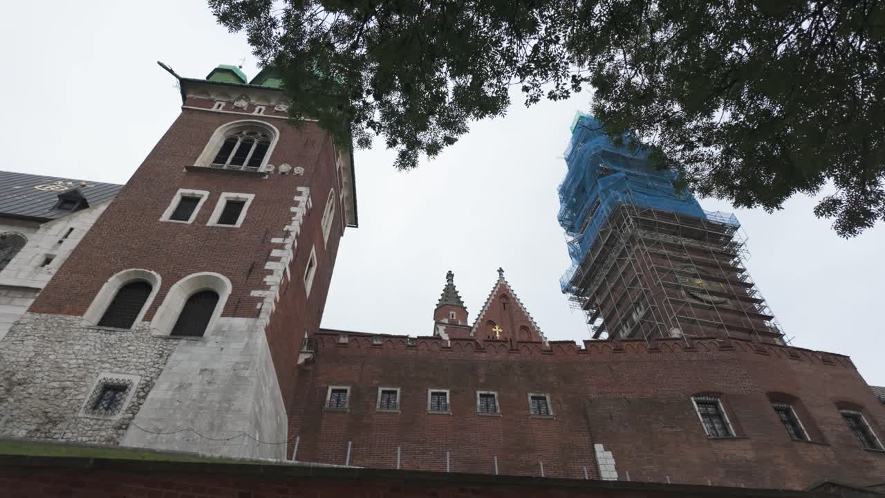 Wawel Cathedral's tower under restoration on a cloudy day with surrounding historical architecture