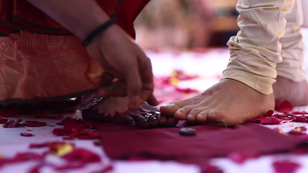 Mani di un sacerdote che officiano un tradizionale rito nuziale dell'India del Sud, con i piedi degli sposi a terra