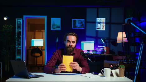 creador de contenido alegre en el estudio revisando un libro de tapa dura recién lanzado