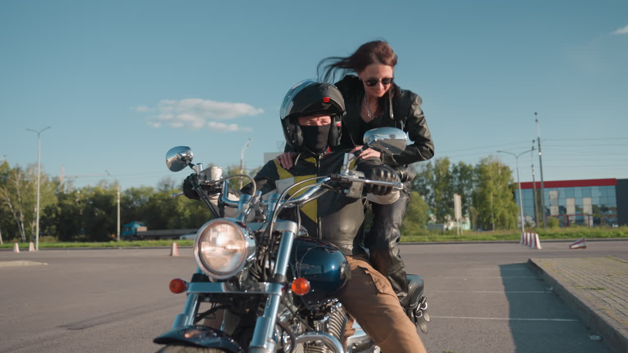 Young girl climbs motorcycle holding rider wearing helmet and leather jacket, urban street setting under daylight sky, chrome details and dynamic biker lifestyle