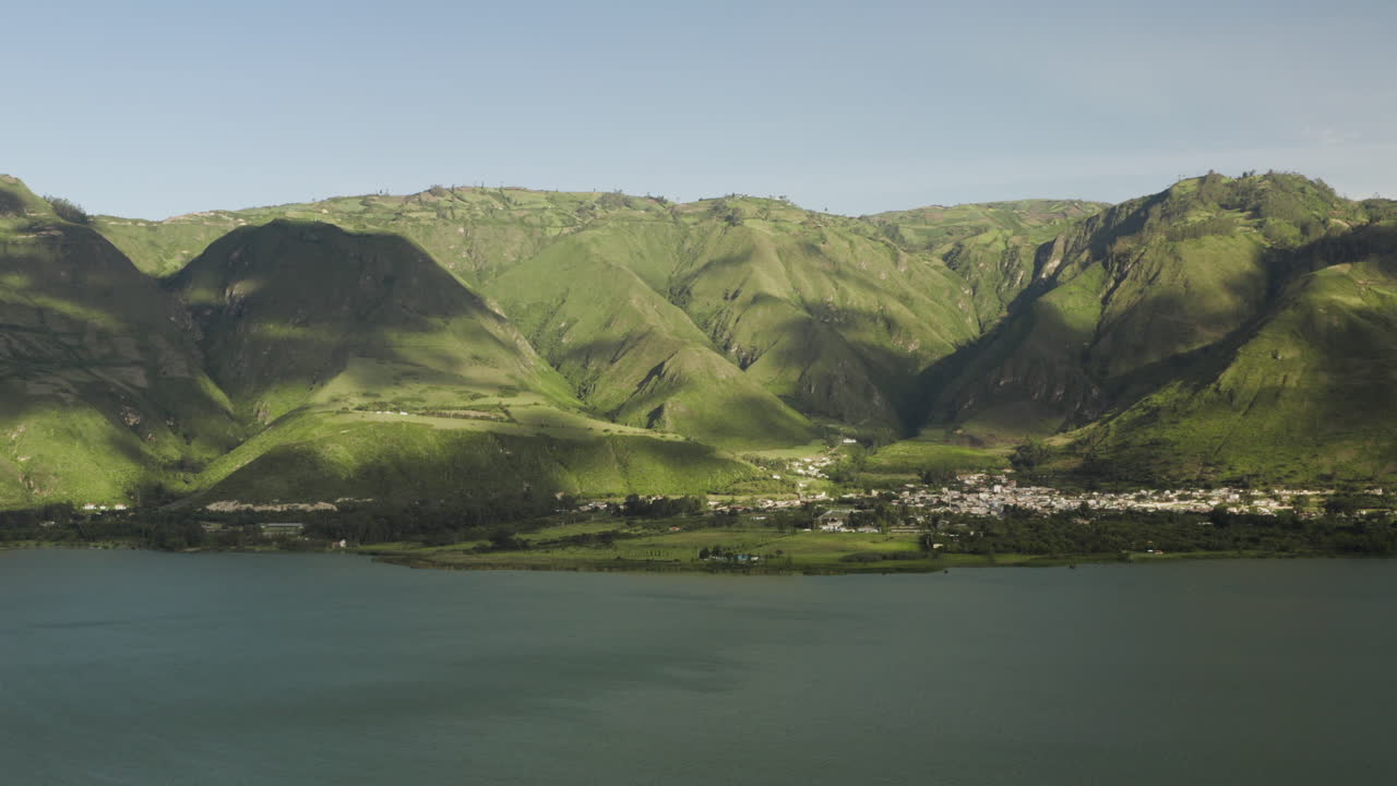 Aerial View of a Lakeside Village Nestled in Lush Green Mountains