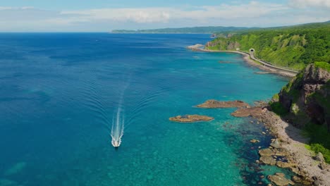 speedboat sails in japanese blue sea beach landscape, aerial drone fly coastline in shakotan hokkaido