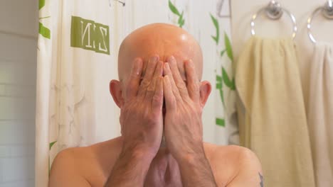 white man washes his face in front of a mirror, reflection view