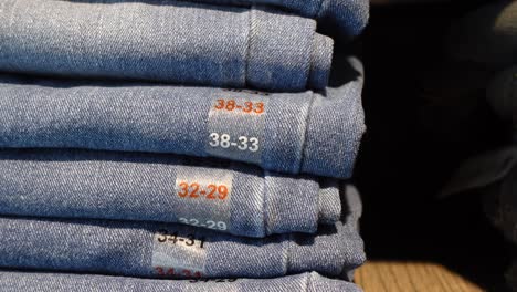 stack of folded blue jeans with size labels