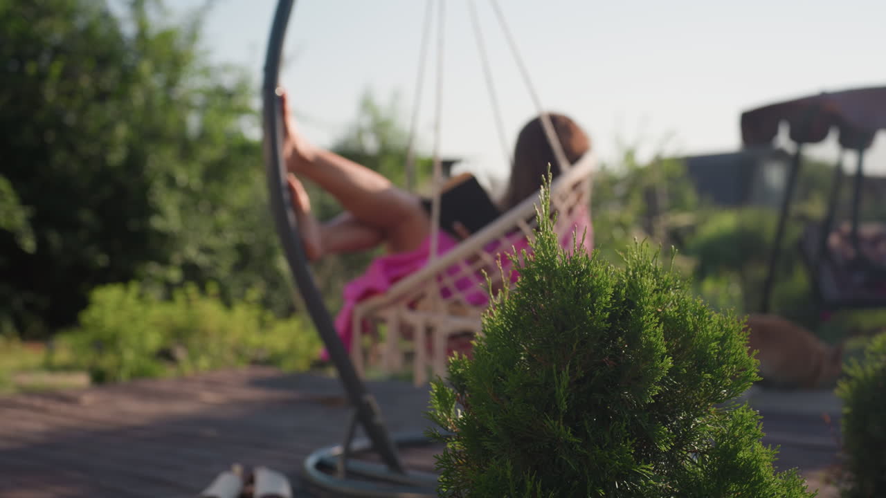 Young Person Enjoying Calm Sunny Day Outdoors, Adolescent Unwinding In Cozy Patio Setting Amidst Flowers, Young Individual Enjoying Tranquil Summer Afternoon On Chair Beside Vibrant Roses