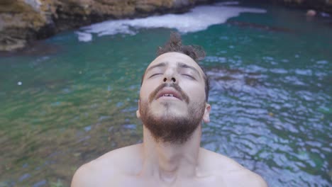 joven abriendo los ojos cerrados en el mar.