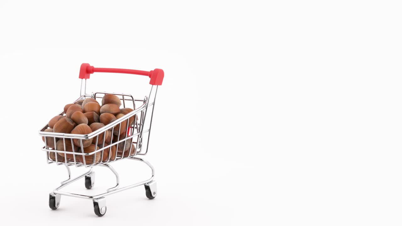 medio marco. macro disparo de un carrito de supermercado lleno de avellanas está girando en la mesa giratoria. aislado en el fondo negro.