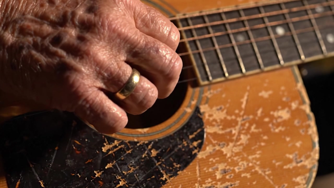 Il tocco di un artigiano: catturare l'eleganza e la maestria del suonare la chitarra tradizionale con un primo piano di una mano che strimpella armoniosamente