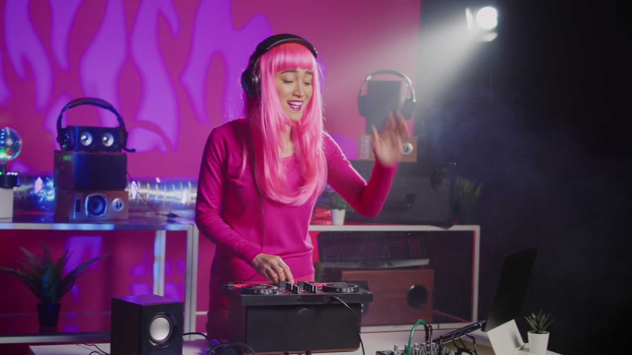 Female DJ performing in a club with pink lighting