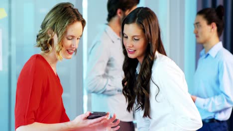 Smiling-business-colleagues-using-mobile-phone