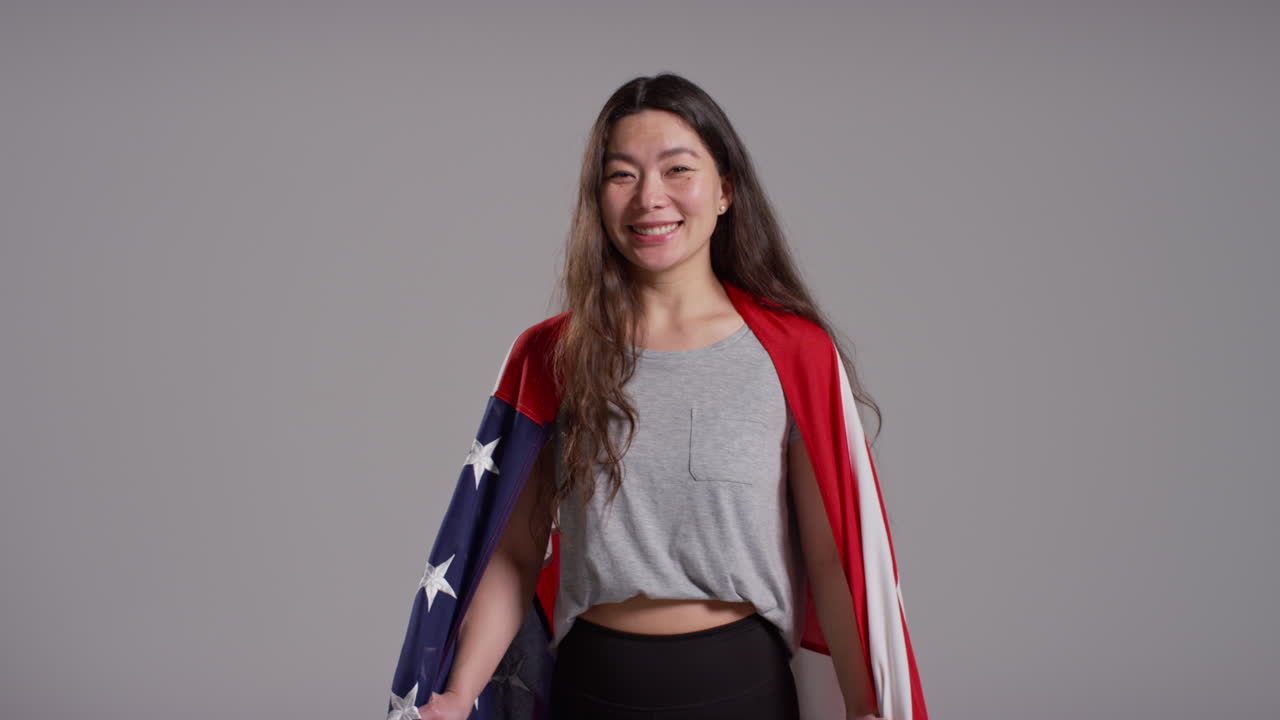 retrato de estudio de una mujer envuelta en la bandera estadounidense celebrando el 4 de julio, día de la independencia.