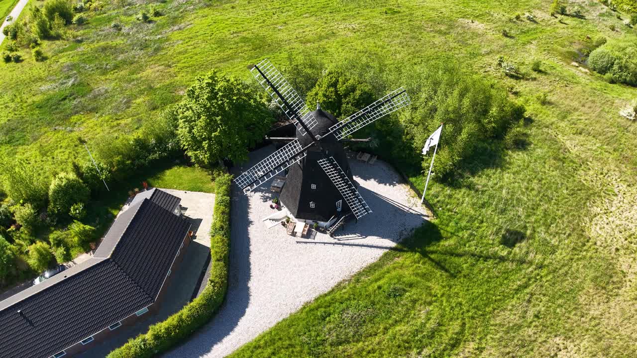 Aerial drone footage of Egå Mill in Denmark, showing the historic windmill surrounded by green fields and countryside in bright daylight