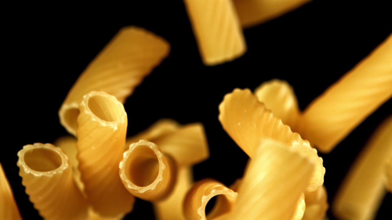 Pasta secca che cade al rallentatore su sfondo nero