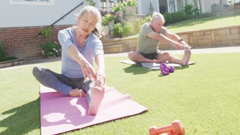 Glückliches,-Vielfältiges-älteres-Paar,-Das-Yoga-Praktiziert-Und-Sich-Auf-Matten-Im-Garten-Dehnt