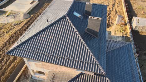 aerial view of house roof top covered with ceramic shingles. tiled covering of building under construction