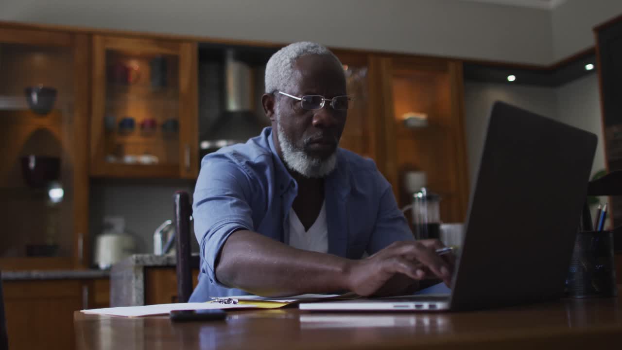 African american senior man using laptop and calculating finances at home