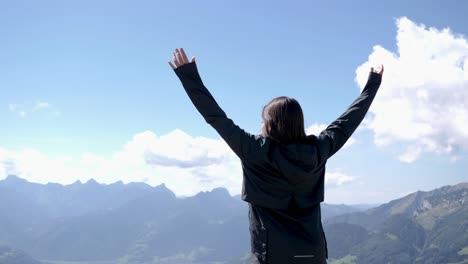 una mujer bonita alcanzó la cima de la montaña y levantó los brazos en el aire en las hermosas montañas de suiza