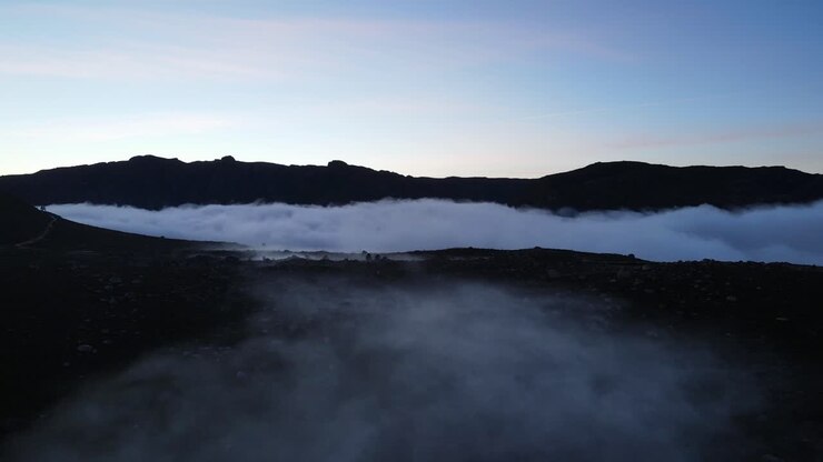 Aerial view of a beautiful foggy rocky land mountain valley after sunset