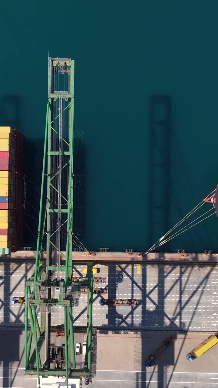 Aerial view of shipping containers being loaded and unloaded at a container terminal. This location illustrates the vital role of freight transportation in global shipping and international trade.