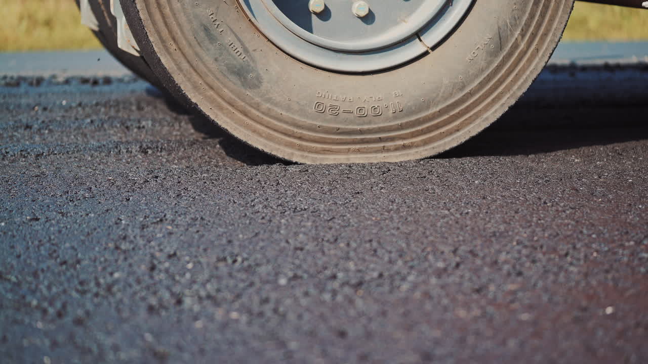 Asphalt spreader in work on site. Close up view of asphalt at the road under construction