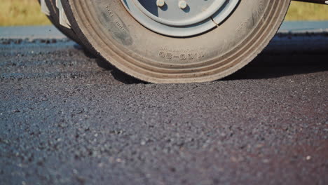 asphalt spreader in work on site. close up view of asphalt at the road under construction