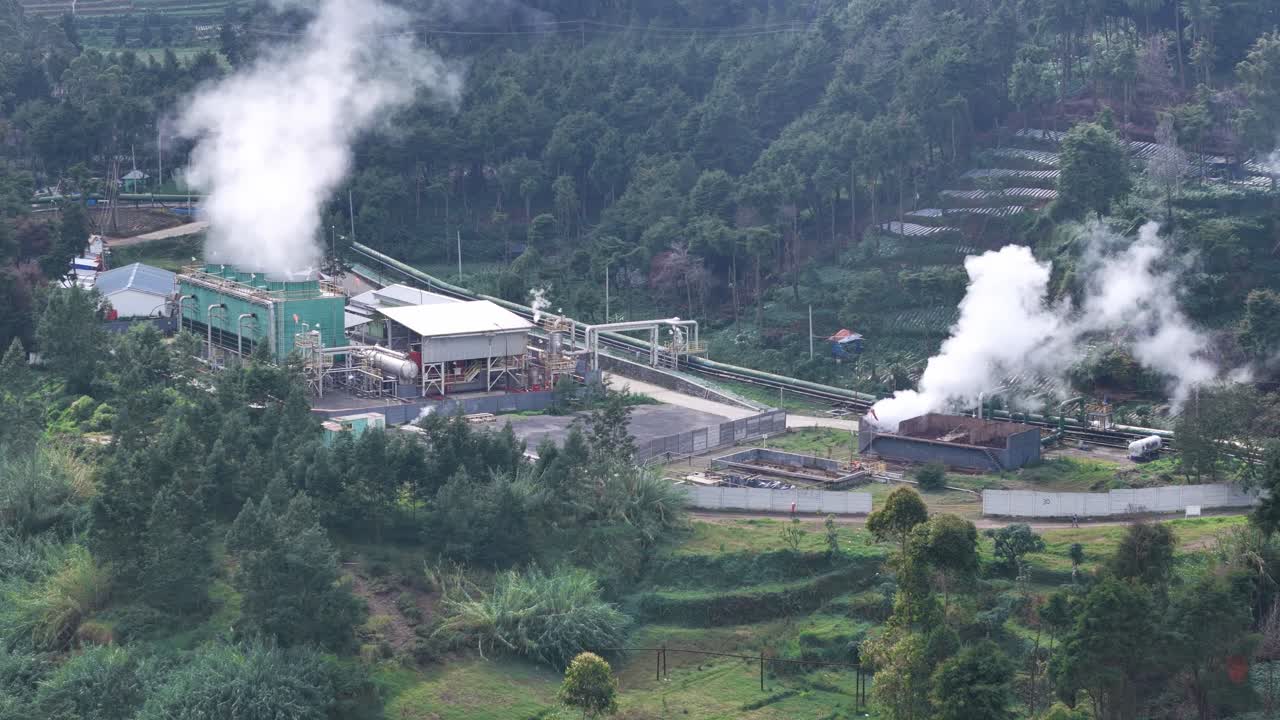 Drone view of a geothermal energy station in a mountainous area, producing clean electricity through natural steam emissions. Dieng, Indonesia