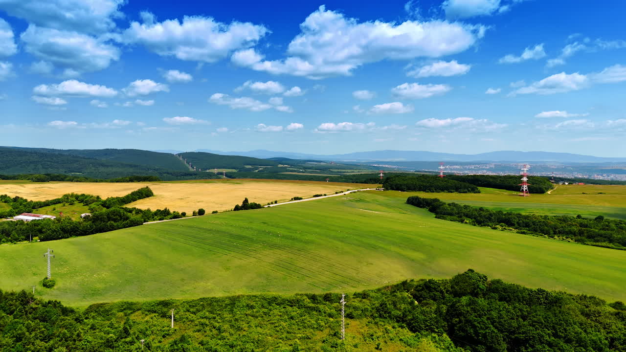 Beautiful landscape view of green fields. Vast fields under a blue sky, with distant hills and towers, showcase the beauty of nature