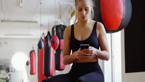 boxeadora usando teléfono móvil en el estudio de fitness 4k