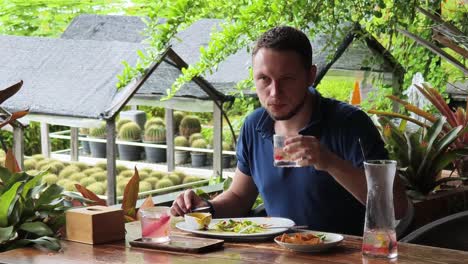 hombre disfrutando de una comida en un restaurante de jardín tropical