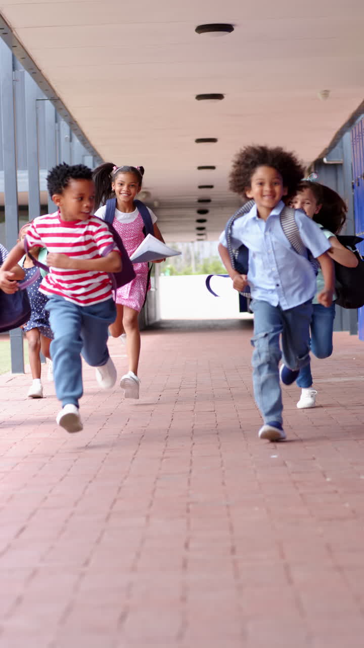 Vertical video: Running in school hallway, group of kids with backpacks smiling and laughing
