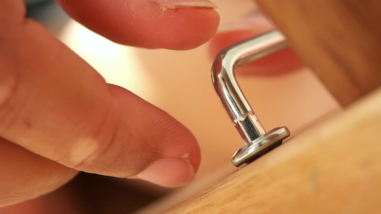 Hand installing a metal cabinet handle