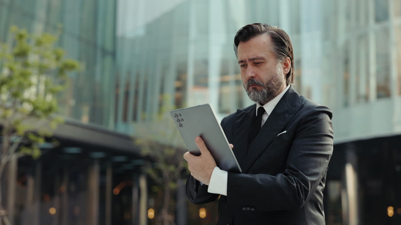Empresário maduro usando tablet digital ao ar livre em frente a edifício moderno