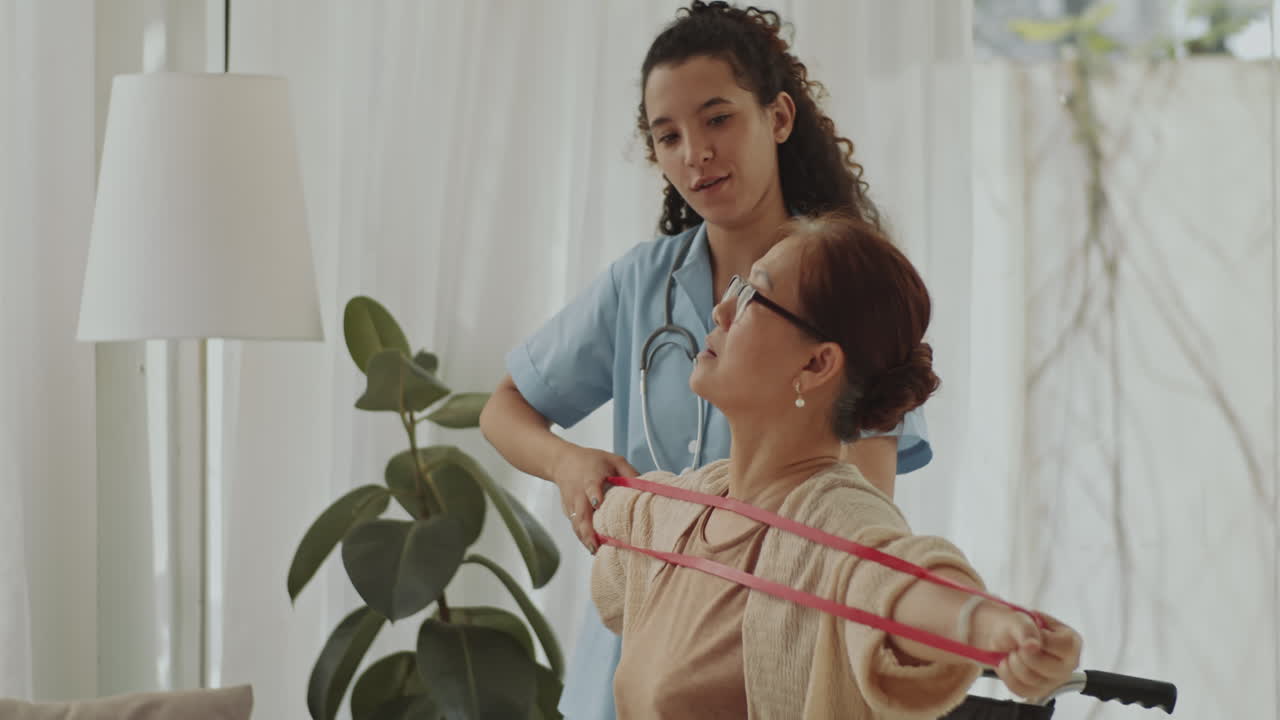 Nurse assisting senior woman with physical therapy using resistance band at home
