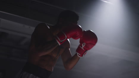 toma de cerca de dos boxeadores masculinos con guantes en el ring de boxeo luchando en un partido de boxe o con una iluminación de bajo nivel 3