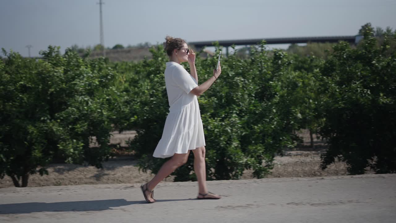 Woman walking in an orchard using a tablet