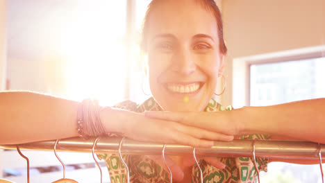 diseñadora de moda apoyada en un estante de ropa