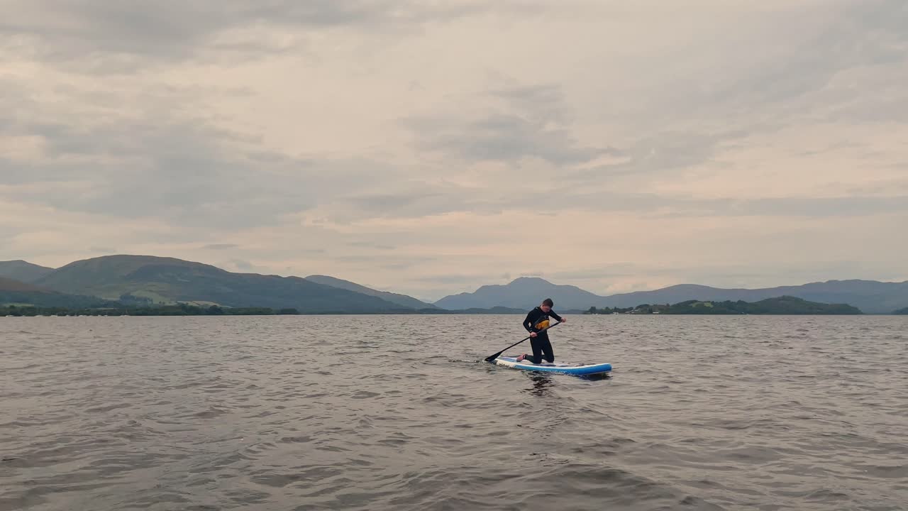 toma estática de un joven que regresa a la costa en su tabla de remo