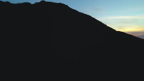 rising drone shot revealing a red sunset with a lone lighthouse off the coast of oregon