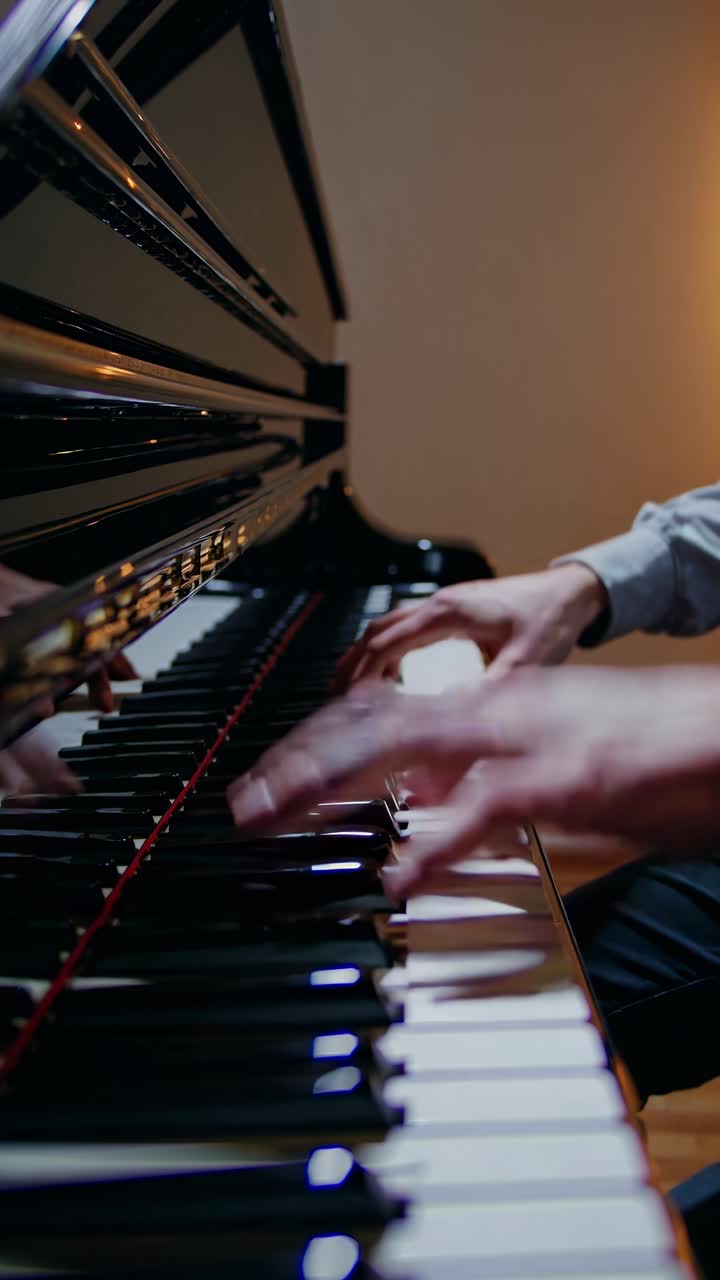 Close-up video of hands playing a piano, captured from a low angle, highlighting the elegance