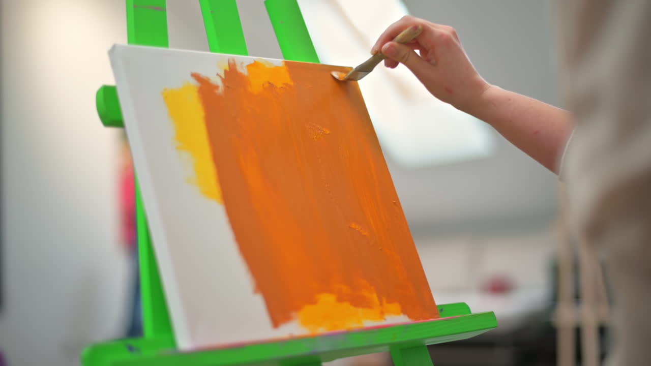 A woman painting a picture using a brush in a studio. Slow motion