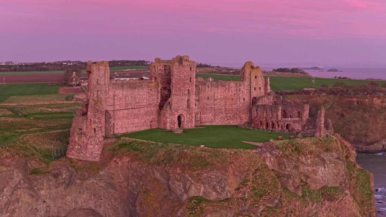 Drone flyver over Tantallon borgruiner ved solopgang