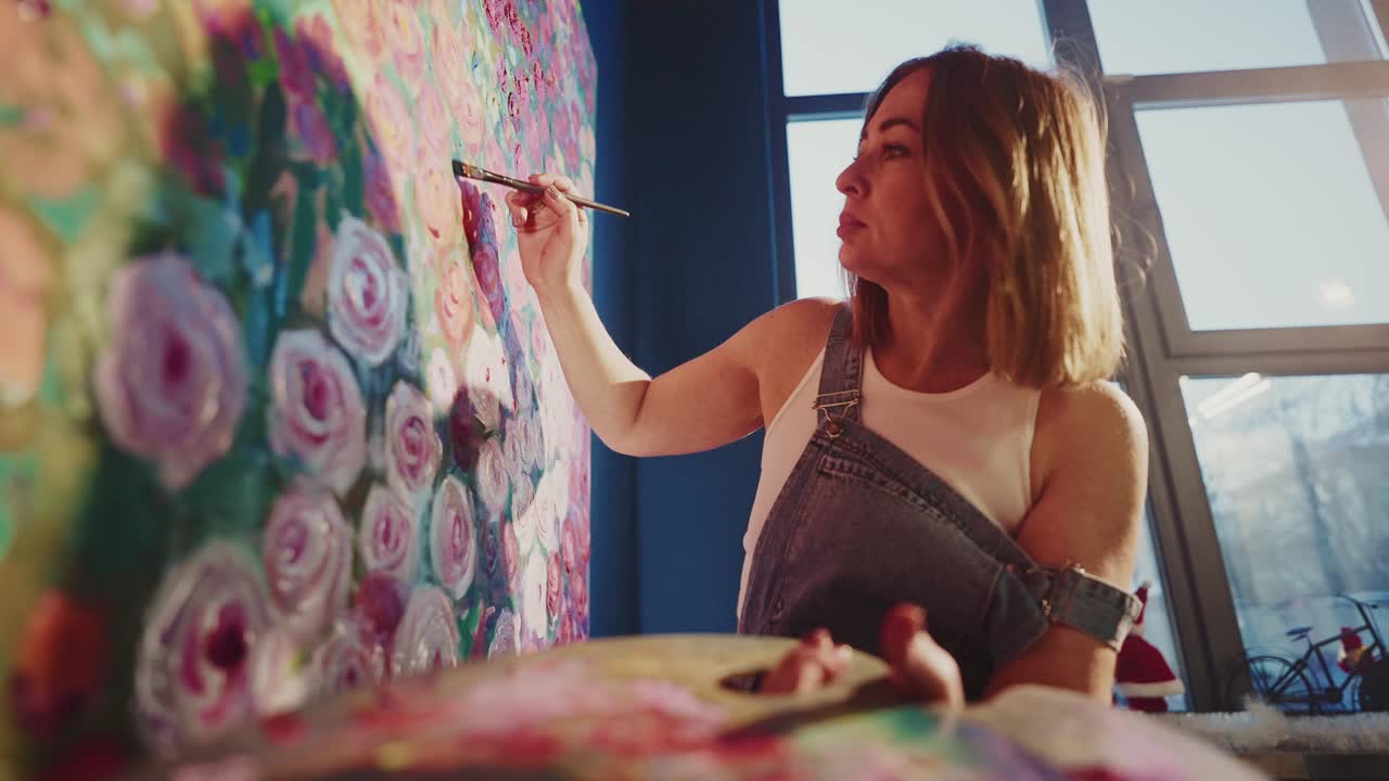 Mulher Artista Concentrada Pintando Obra Floral em Estúdio Iluminado