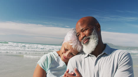 smiling senior african american couple embracing at the beach