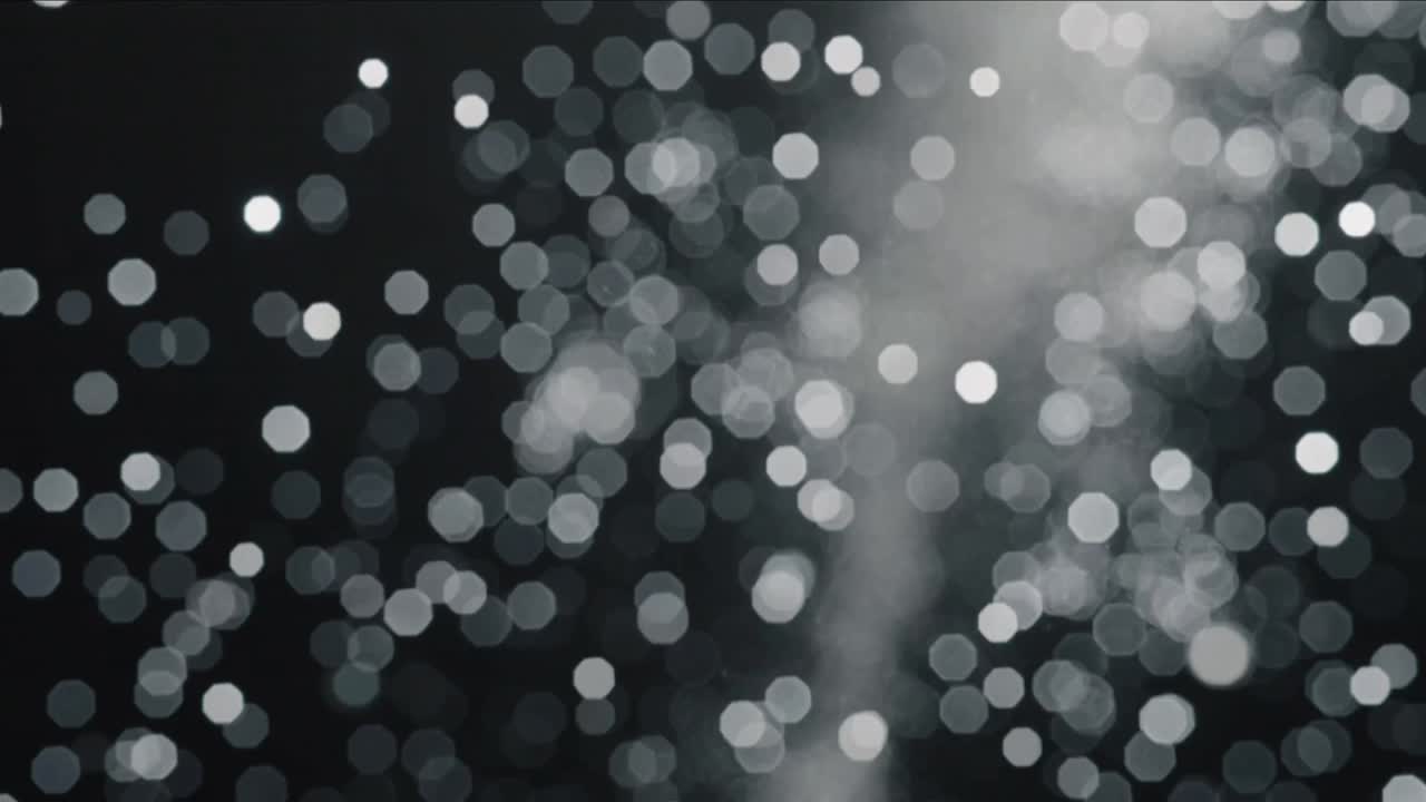 Shifting frames showing dense bokeh highlights drifting across dark backdrop, plume forming