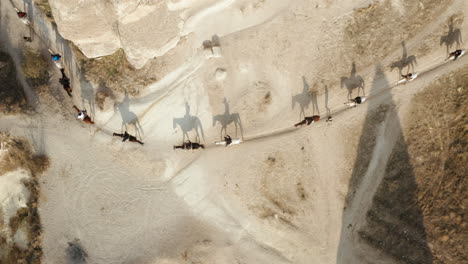 Vista-Superior-De-Hombres-Turcos-Montando-A-Caballo-Pasando-Por-Un-Camino-De-Tierra-Curvo,-Capadocia,-Turquía