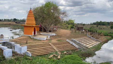 aerial shot of a beautiful temple in a village in india with river flowing near it